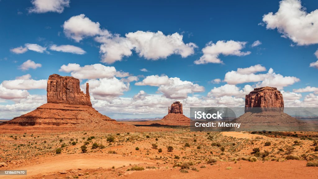 The Mittens and Merrick Butte Monument Valley Panorama The Mittens - West Mitten, East Mitten and Merrick Butte Panorama View Over Monument Valley under beautiful cumulus clouds summer skyscape. Monument Valley, Arizona, USA, North America. Arizona Stock Photo