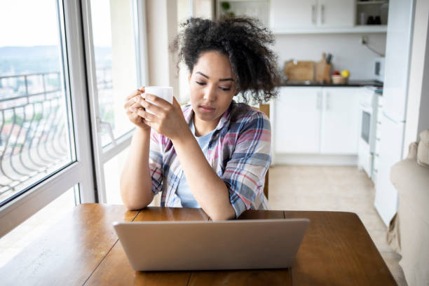 istock Woman drinking coffee and using laptop at home 1218607930
