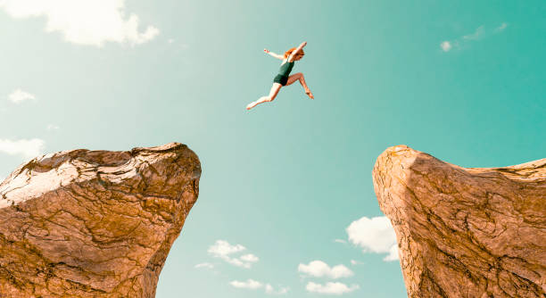 mulher faz salto perigoso entre duas formações rochosas - challenge chance conquering adversity opportunity - fotografias e filmes do acervo