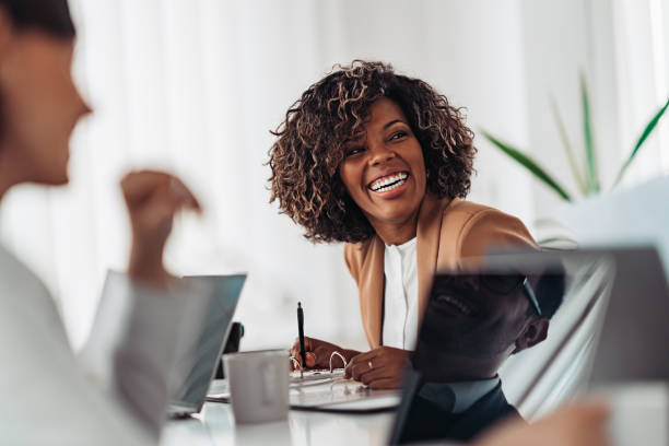 Portrait of cheerful businesswoman smiling at the meeting Portrait of cheerful african american businesswoman discussing and smiling at the meeting with colleagues one young woman only photos stock pictures, royalty-free photos & images