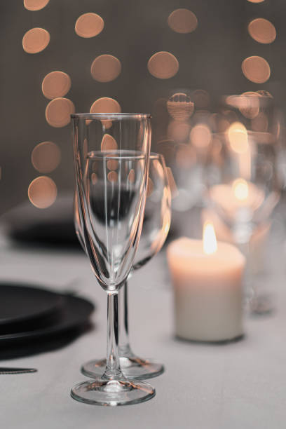istock A table set in the restaurant. Serving a table. Grey artistic background. Black matte utensils, glass glasses. White candles and decor. Festive yellow lights garland in the background. 1218610933