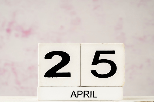 White cube calendar for April against soft pink background with copy space