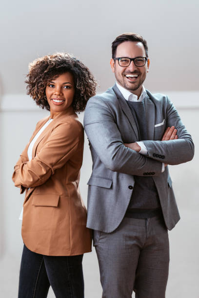 Three quarter length business portrait of cheerful multi ethnic couple Three quarter length business portrait of cheerful multi ethnic couple wearing suit and looking at camera african american business couple stock pictures, royalty-free photos & images