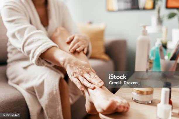 Woman With Beauty Face Mask Massaging Her Legs And Feet Stock Photo - Download Image Now