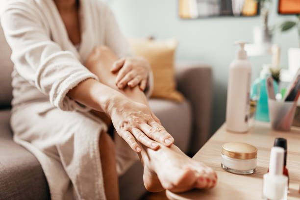 woman with beauty face mask massaging her legs and feet - massage creme imagens e fotografias de stock