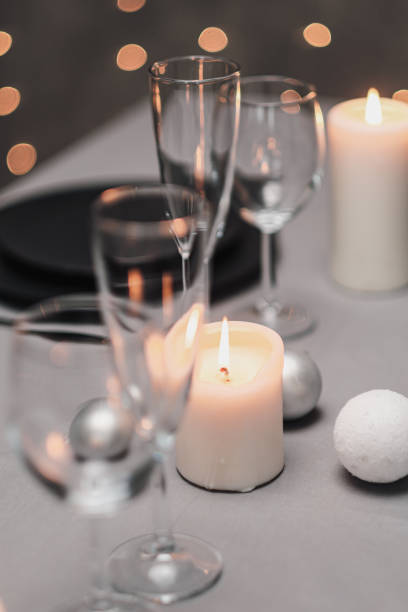 istock A table set in the restaurant. Serving a table. Grey artistic background. Black matte utensils, glass glasses. White candles and decor. Festive yellow lights garland in the background. 1218613620