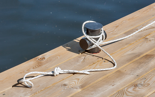 wooden pier at river closeup with rope and mooring post