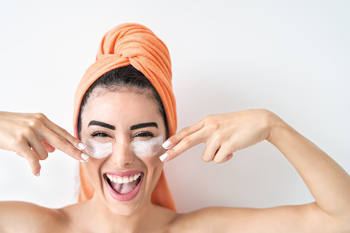 Happy girl applying daily facial cream - Young woman having skin care spa day - Beauty clean treatment and cosmetology products concept