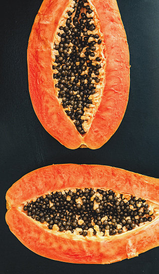 Cut Papaya over orange table background for tropical fruit design concept, top view copy space.