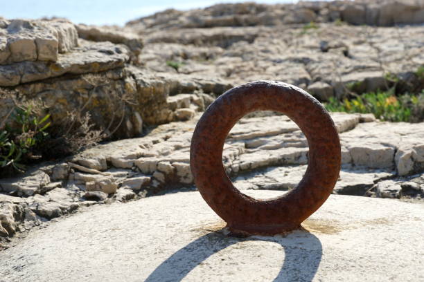 anello arrugginito sulla pietra al sole di mezzogiorno. vecchio anello in metallo vintage per ormeggio barca di mare - noontime foto e immagini stock