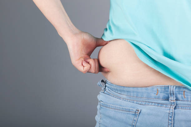 istock woman hand belly fats 1218618311