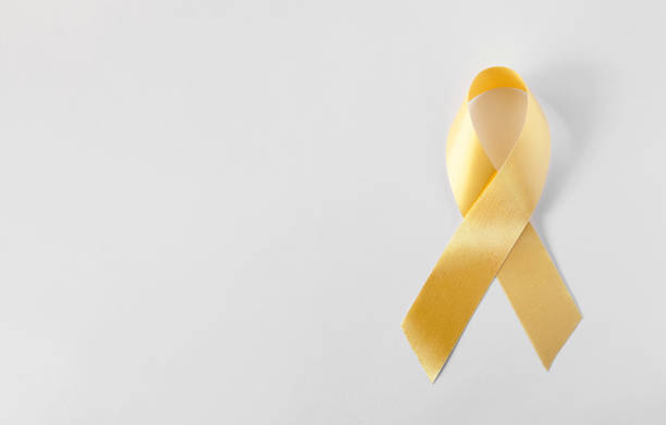 złota symboliczna wstążka - problem raka dzieciństwa. - cancer victim zdjęcia i obrazy z banku zdjęć