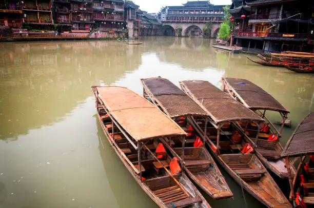 Weathered wooden tourist boats docked on the edge of the Tuojiang river in Fenghuang village morning view in zhejiang province china.