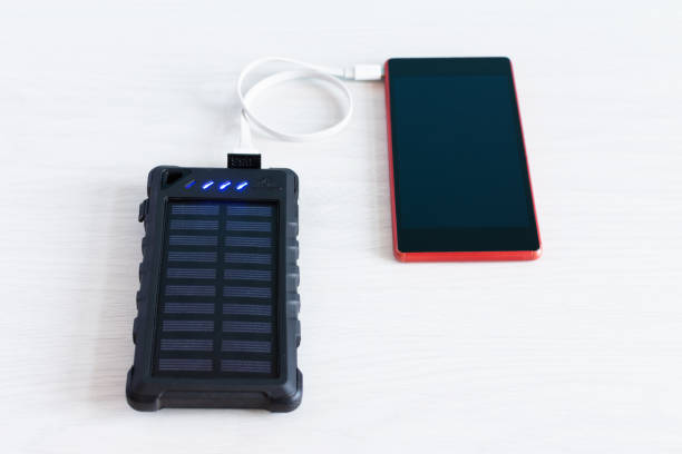 istock Smartphone connected to solar battery panel charger top view on white wooden background. 1218627273