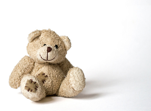 a cute and ridiculous baby soft toy teddy-bear sitting on a bright background
