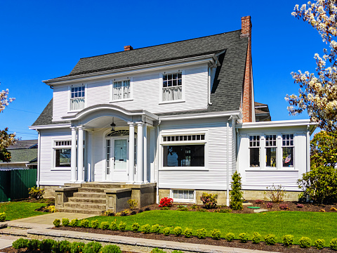 Photo of a white American colonial style home exterior on a sunny spring day with clear blue sky