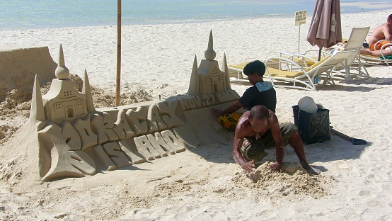 Boracay / Philippines- November 2009 : Local man and his daughter is making a sand castle at the beach with Boracay written on it