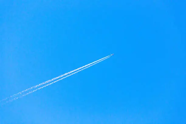 An airplane flying with contrail in the blue sky
