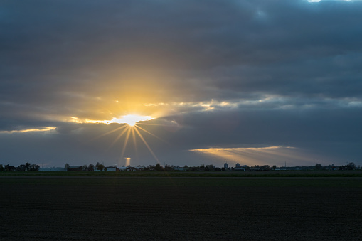 Sun breaks through the clouds. Beautiful sun beams or crepuscular rays over the dutch landscape.