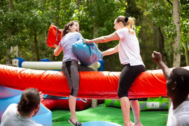 istock Women fighting by pillows on inflatable beam 1218635184