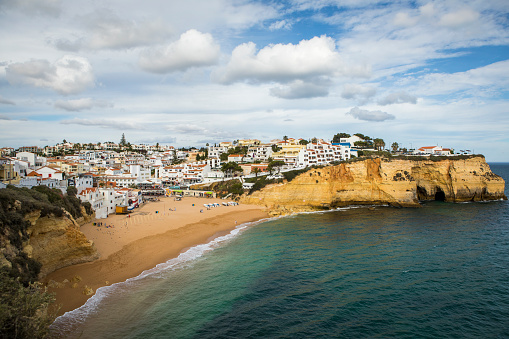 Wide sandy beach between cliffs and in front of charming white architecture in Carvoeiro, Algarve, Portugal