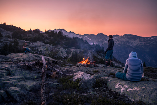 Group of friends enjoying fire while camping outdoors, in an alpine wilderness near Whistler, BC, Canada.