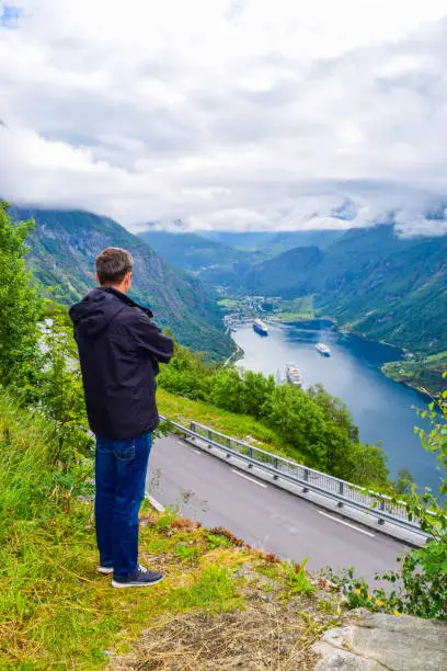 Photo of Tourist man looks at cruise liners at the end of Geirangerfjord, near small village of Geiranger.