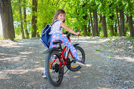 Outdoor portrait of a little girl on her bike in the Park. Sport and a healthy lifestyle.