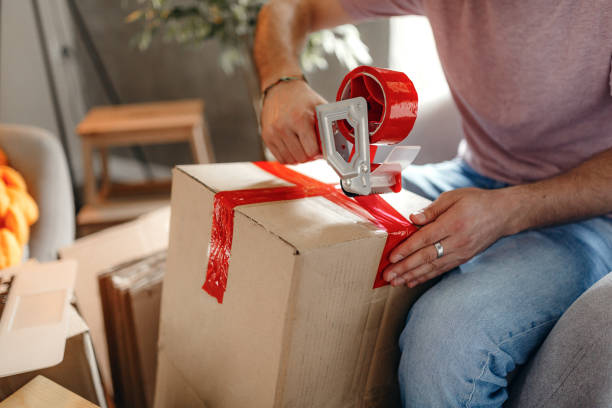 istock Man using duct tape to stick the box together 1218647653
