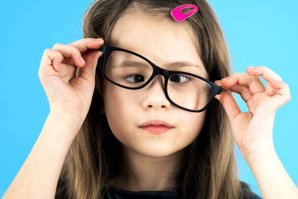 feche o retrato de uma criança de olhos cruzados usando óculos de vista isolados em fundo azul. - pensive only baby girls baby girls baby - fotografias e filmes do acervo