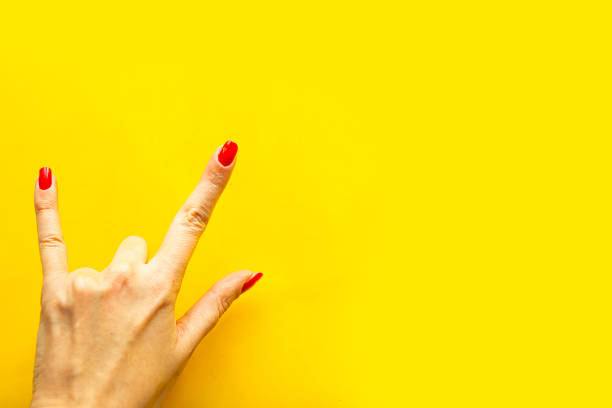 istock Woman's hand shows a gesture Rock over bright yellow background. Copy space for the text 1218648780