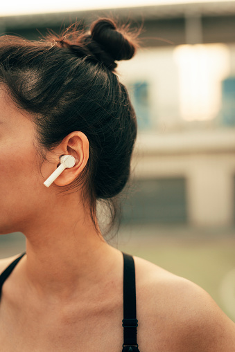 Cropped shot of a woman in sportswear wearing wireless earphones.