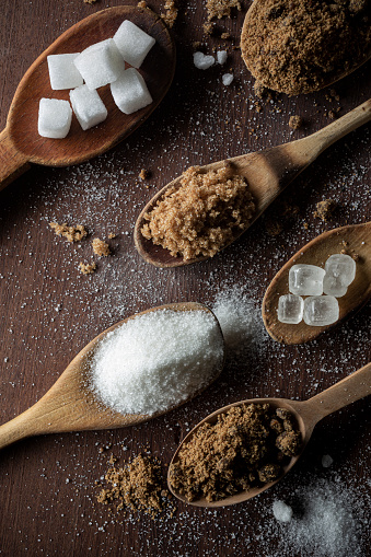 Composition with different presentations of sugar. Top to bottom: Sugar cubes, panela (raw sugar), brown (turbinated) sugar, sugar crystals (rocks), white granulated sugar and panela again.