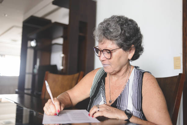 istock Senior woman taking notes or filling forms at home 1218652753