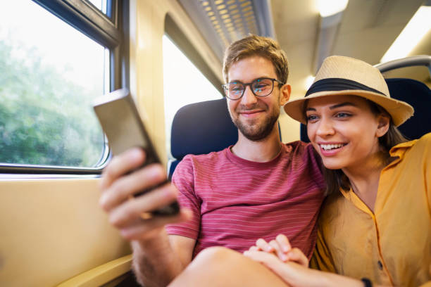 istock Young beautiful couple enjoying riding on the train while looking at phone together 1218656989
