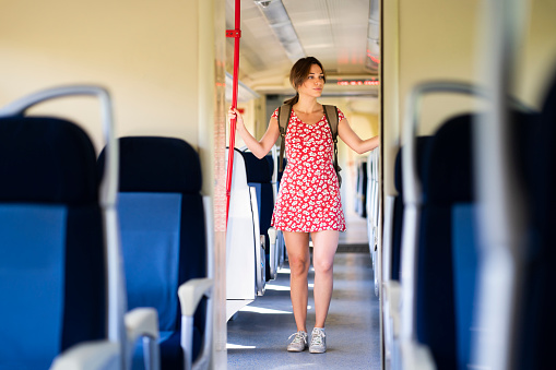 Young caucasian woman walking the empty passenger wagon while riding on the train