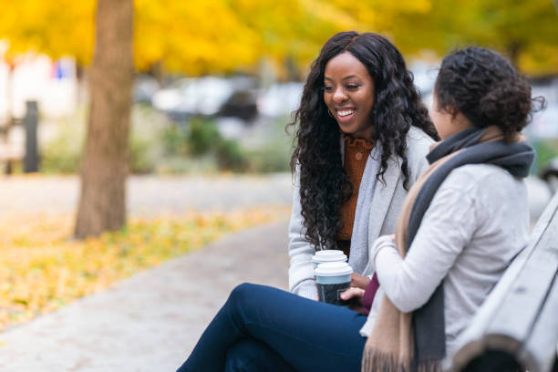 istock Two women talking while relaxing at public park 1218659368