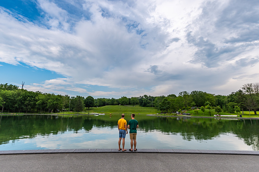 Young homosexual couple visiting the Beaver lake on the Mount Royal, Montreal, during summer.