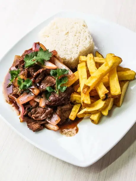 Photo of Traditional Peruvian dish Lomo Saltado (Beef saltado). Lomo saltado is a stir fry that typically combines marinated strips of sirloin with onions, tomatoes, french fries and typically served with rice.