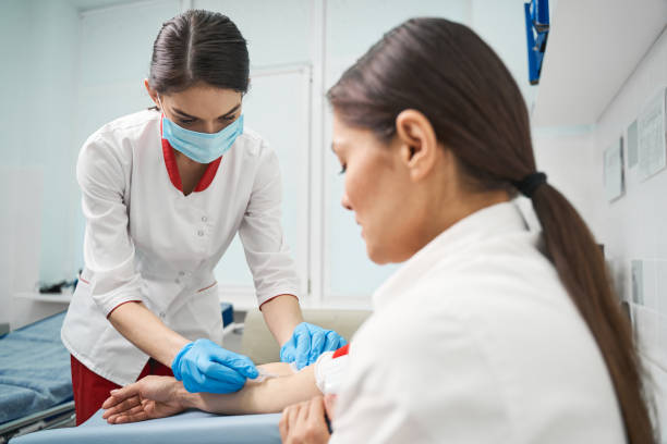 istock Serious medical worker looking at place for injection 1218681143