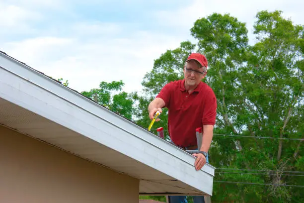 Photo of Wind mitigation inspection inspector on a ladder doing inspection on new roof to generate a risk rating