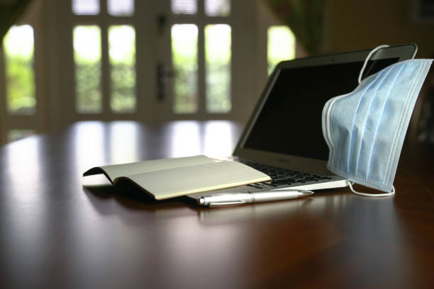 istock Medical face mask on top of computer laptop on the table. 1218686796