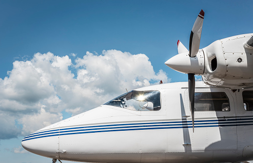 Modern plane with propellers side-view on a background of blue sky with white clouds. Aircraft exterior.