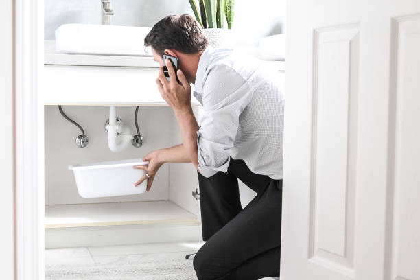 istock Sad Young Man Calling Plumber In Front Of Water Leaking From Sink Pipe 1218688981
