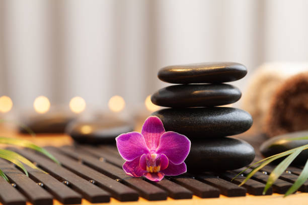 Massage stone stack, orchid flower and burning candles. Spa and beauty background.