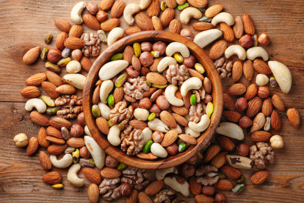 Wooden bowl with mixed nuts on rustic table top view. Healthy food and snack. stock photo