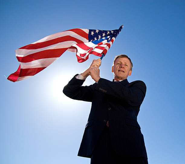 Man standing in front of an American flag.Please also see: