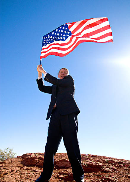 Man standing in front of an American flag.Please also see: