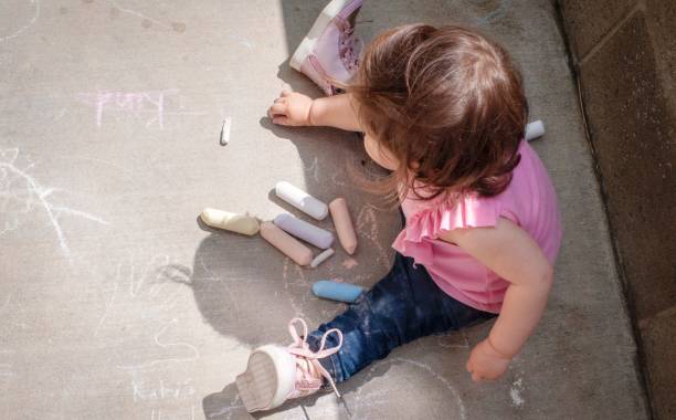 istock Girl drawing with chalk on the sidewalk 1218705133