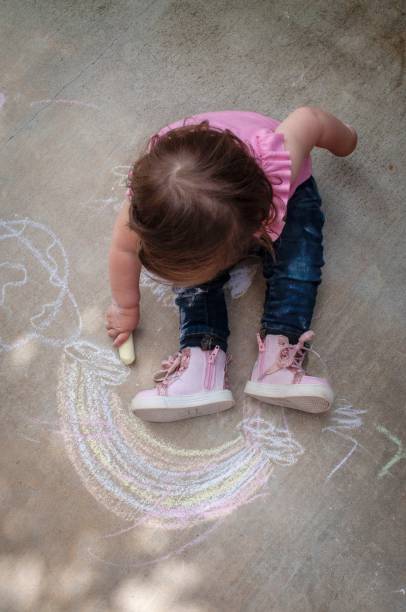 istock Girl drawing with chalk on the sidewalk 1218705142